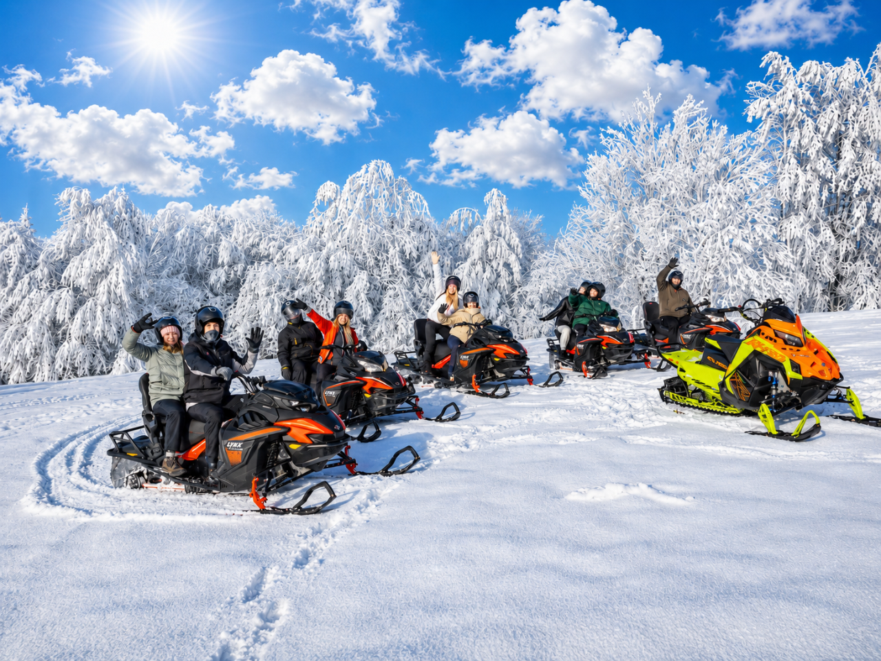 Group snowmobile tour in a winter field A group of people on colorful snowmobiles waving at the camera in a snowy Tatra field surrounded by frosted trees