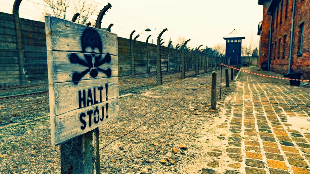 Auschwitz museum warning sign and electrified barbed-wire fence